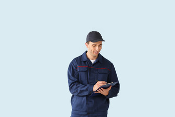 Obraz na płótnie Canvas Male car mechanic with clipboard on color background