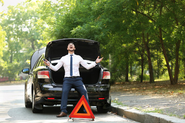 Stressed businessman near broken car outdoors