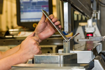 worker operating metal press machine at workshop.