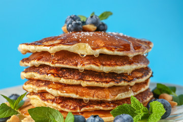 Tasty pancakes and blueberries on color background, closeup