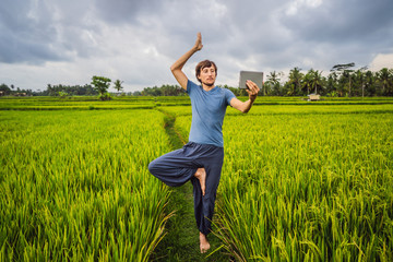 Fototapeta na wymiar Handsome man learns to do yoga, watch educational video on tablet