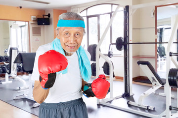 Senior male boxer standing in the gym center