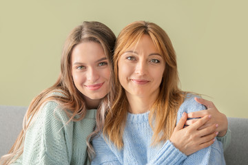 Happy mother and daughter sitting on sofa at home