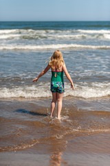 Fototapeta na wymiar Young blonde girl paddling in the sea on a sunny day