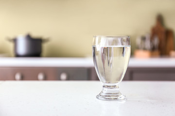 Glass of fresh water on table in kitchen