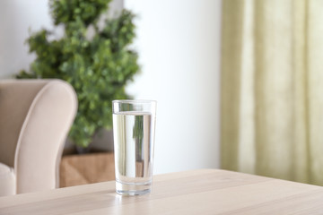Glass of fresh water on table in room