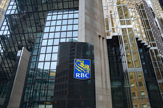 The logo of RBC, Canada's largest banking company, on its modern head office building in Toronto's financial district, with a bike share station in front.