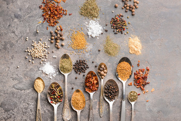 Spoons with different spices on grunge background