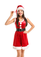 Beautiful young woman in Santa Claus costume and with candy cane on white background