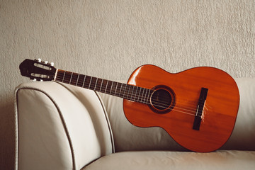 Isolated acoustic guitar on a couch with lights and shadows