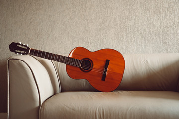 Isolated acoustic guitar on a couch with lights and shadows