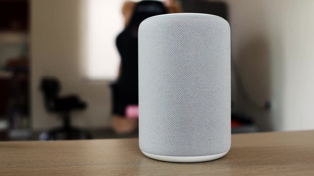 Gray smart speaker with cloth texture. Panning movement to the subject until it's on focus.