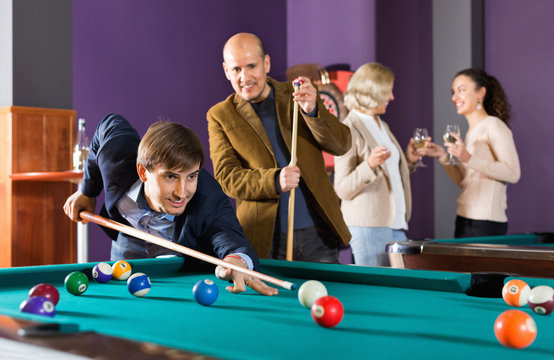 Group of happy friends playing billiards