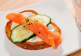Toasted bread with creamy sauce, salmon and cucumber