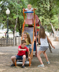 Kids sliding down together on playground's construction