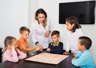Boys and little girls playing at board game