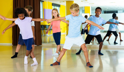  boys and girls dancing rock-and-roll in pairs with female trainer