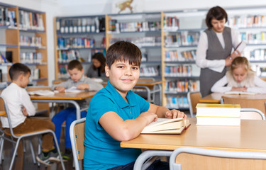Fototapeta na wymiar Іmiling boy reading in school library