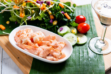 Fresh salad plate with shrimp, salmon, tomato and mixed greens  on wooden background .