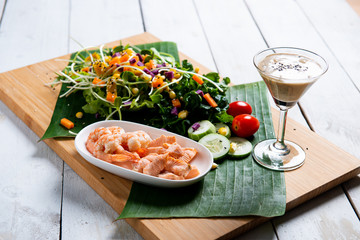 Fresh salad plate with shrimp, salmon, tomato and mixed greens  on wooden background .