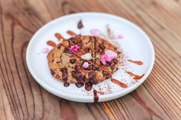 chocolate cookie with caramel on cerabic dish with flower on wooden table