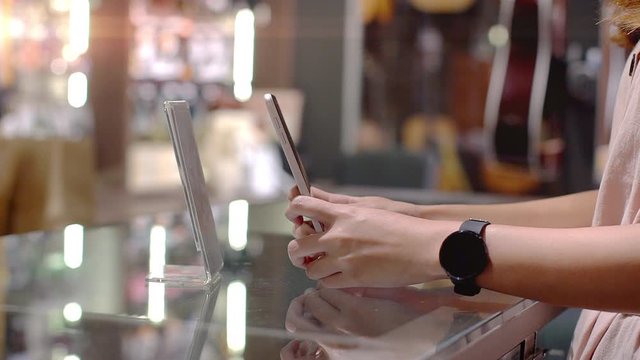 Young Asian woman using mobile phone to purchase product at the point of sale terminal in a retail store with near field communication nfc  radio frequency identification payment technology