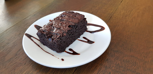 Chocolate brownie in white plate on wood table background
