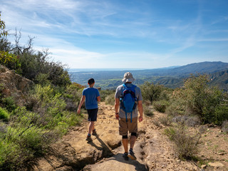 Father and son hiking on Jesusita Trail with panoramic view of ocean and Channel Islands, Santa Barbara, California, USA