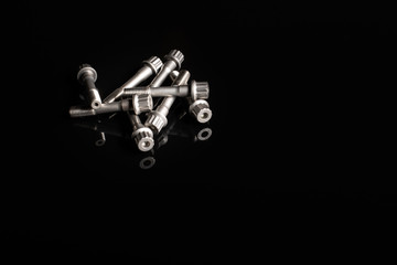 con rod bolts on a black reflective background