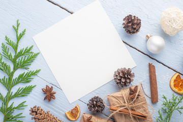 Flat lay Christmas composition with a white card for design with Christmas tree branches, Christmas toys, and space for design