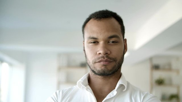 Front view of confident African American man looking at camera. Young bearded guy posing at office. Concept of confidence