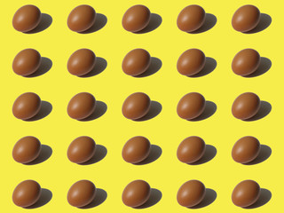 Pattern of brown chicken egg with reflection on yellow background. Minimal food fashion concept.