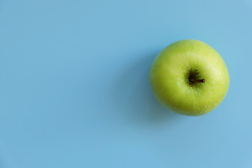 A ripe green apple fruit isolated on blue background with copy space for text. Top view.