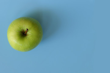 A ripe green apple fruit isolated on blue background with copy space for text. Top view.