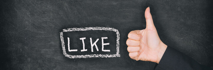 Like button drawing on black chalkboard illustrating social media button thumbs up business woman's hand closeup against blackboard banner panoramic background.