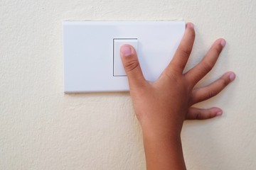 Close up thumb finger’s kid is turning on or turning off the light-switch.