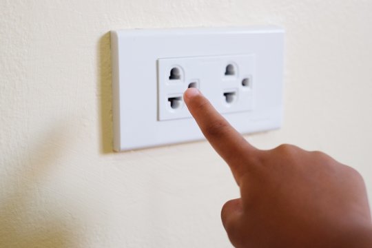 Close up  kid put her finger in to electrical socket. child at risk of electric shock. Safety concept.