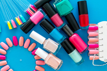 Сhoose nail polish. Polishes and color samples on blue background top view mockup