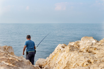 Fototapeta na wymiar fisherman with fishing rod on the seashore.
