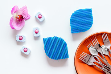 Dry detergent for dishwashing near plates and orchid flower on white background top view