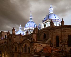 Obraz premium Famous domes of the New Cathedral in Cuenca, Ecuador rise over the city skyline at dusk.
