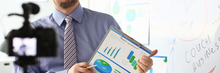 Male in suit and tie show stats graph pad making promo videoblog or photo session in office...