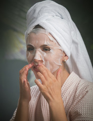 close up portrait of nice young woman applying facial mask