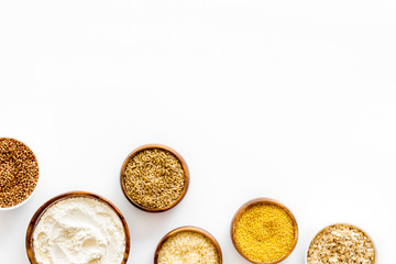 Set of cereals - rice, oats, buckwheat - in bowls on white table top view frame copy space