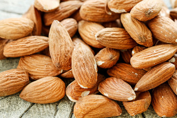 Almonds on rough wooden background, raw fruits.