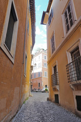 Empty narrow cobblestone street going among old houses with shabby yellow walls in the historical center of the city