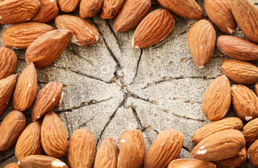 Almonds on rough wooden background, raw fruits.