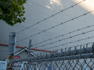 Barbed wire on steel chain link fence blowing entry to warehouse