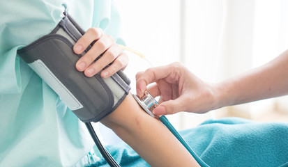 At the hospital, the doctor is checking the symptoms and checking the patient's pressure.