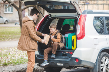 father with son packing bags to car trunk. car travel concept